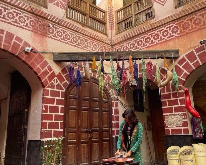Viajera preparando especias en el patio de un riad decorado con lana teñida en Marrakech