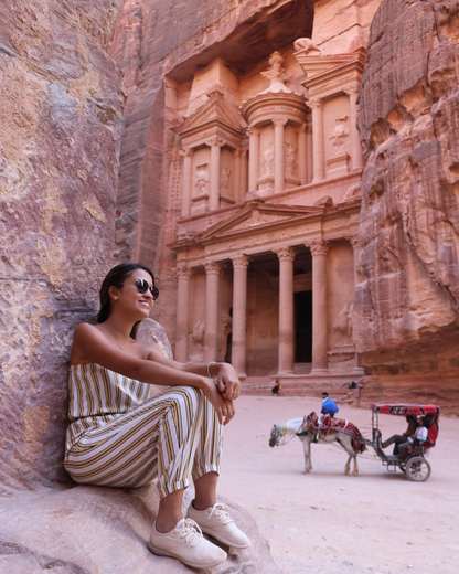 Viajera sentada en las rocas frente al Tesoro de Petra, Jordania